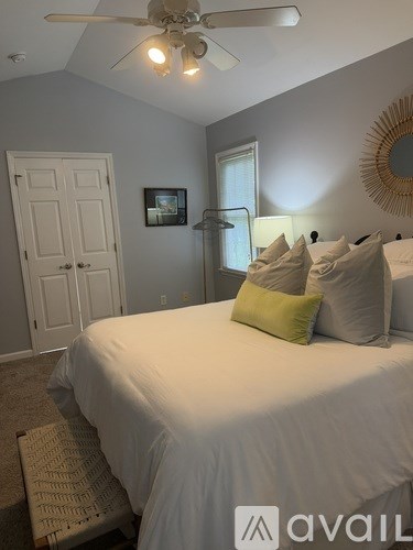 A bedroom with a bed, a ceiling fan, and a mirror on the wall.