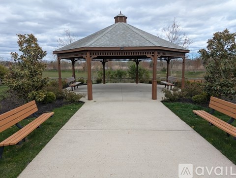 A gazebo with a concrete walkway and benches on either side.