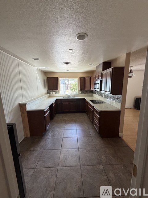 A kitchen with brown cabinets and a tile floor.