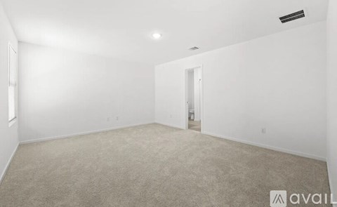 A spacious room with beige carpeting and white walls.
