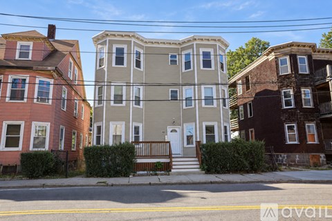Three houses with different facades are lined up on a street.