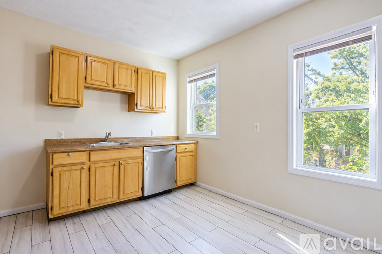 A kitchen with wooden cabinets and a window overlooking trees.