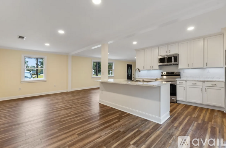 A spacious kitchen with white cabinets and a wooden floor.