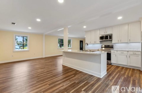 A spacious kitchen with white cabinets and a wooden floor.