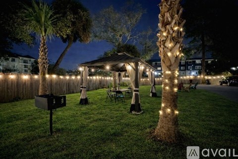 A backyard with a gazebo, palm tree, and string lights.