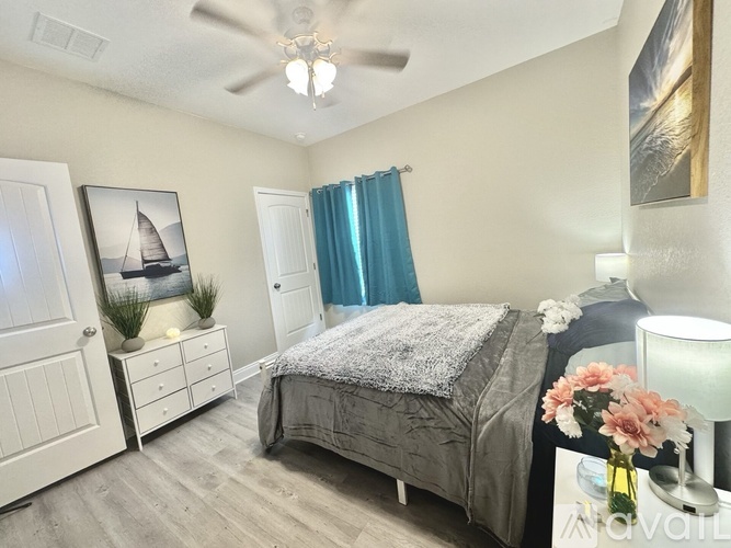 A bedroom with a bed, dresser, and a ceiling fan.