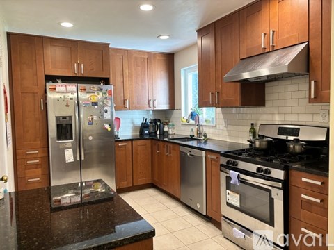 A kitchen with brown cabinets and a black countertop.
