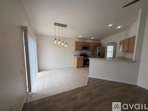 A spacious living room with a kitchen area in the background.
