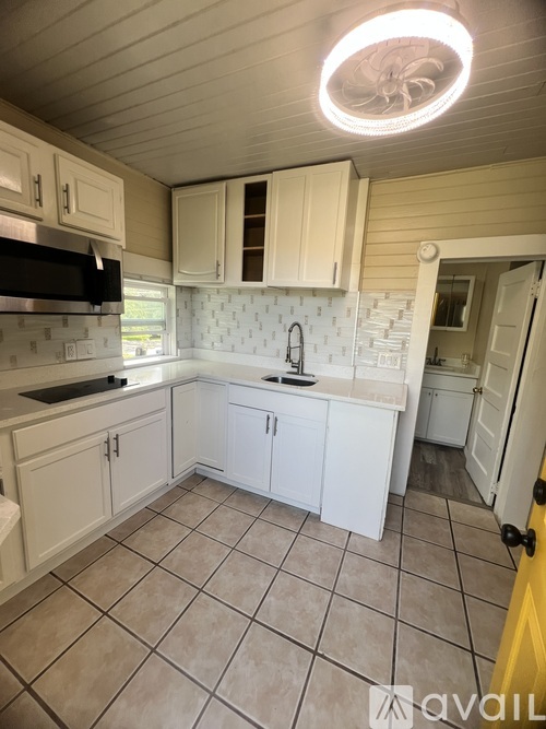 A kitchen with white cabinets and a black microwave.