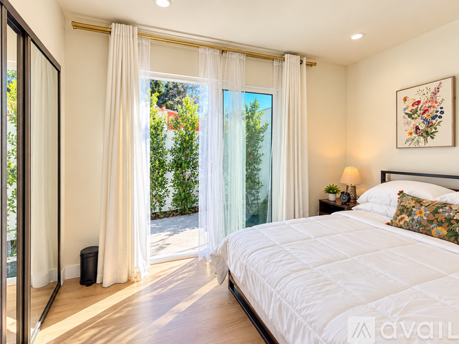 A bedroom with a large bed and a view of trees through the window.