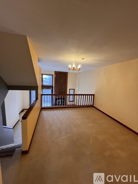 A spacious room with a carpeted floor and a chandelier hanging from the ceiling.