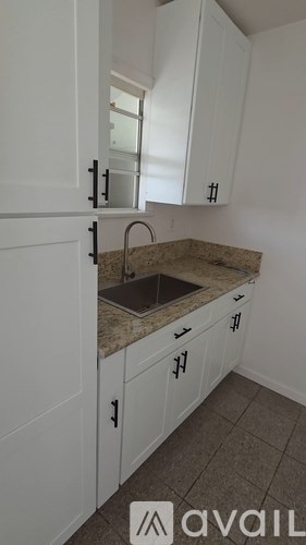 A kitchen with white cabinets and a granite countertop.