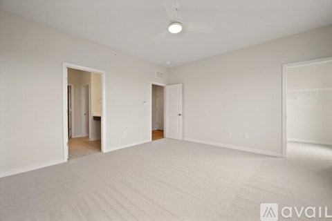 A spacious room with white walls and carpeted floor.