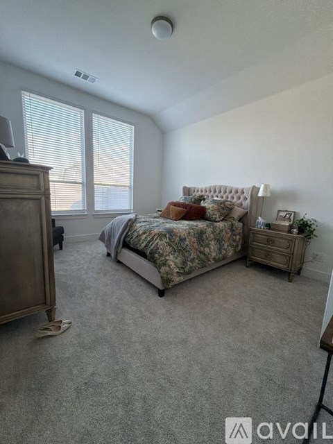 A bedroom with a bed, dresser, and window with blinds.
