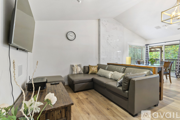 A living room with a grey couch, a wooden table, and a television mounted on the wall.