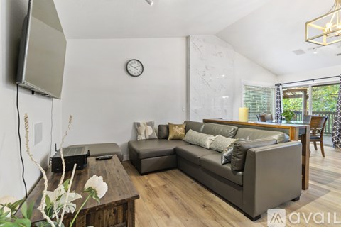 A living room with a grey couch, a wooden table, and a television mounted on the wall.