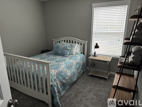 A bedroom with a white bed and a blue patterned bedspread.