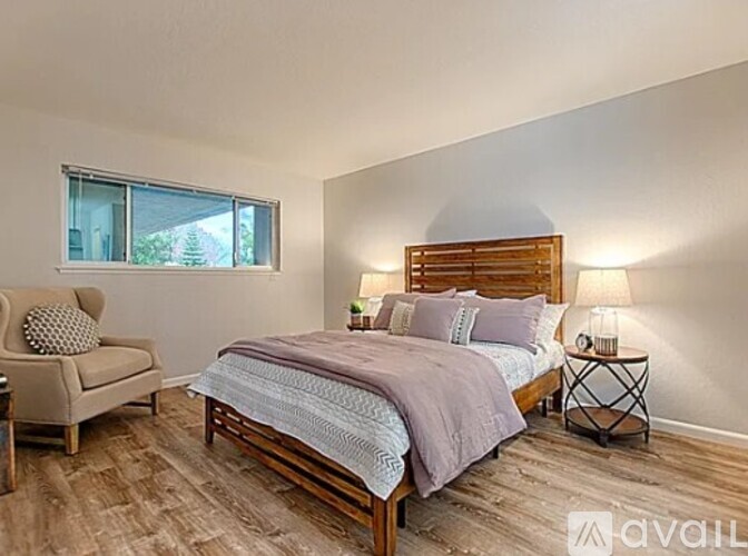 A bedroom with a bed, chair, and window.