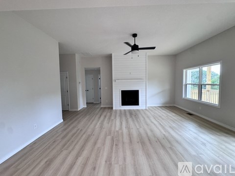 A spacious living room with a fireplace and a ceiling fan.