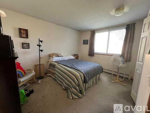 A bedroom with a bed, dresser, and window.