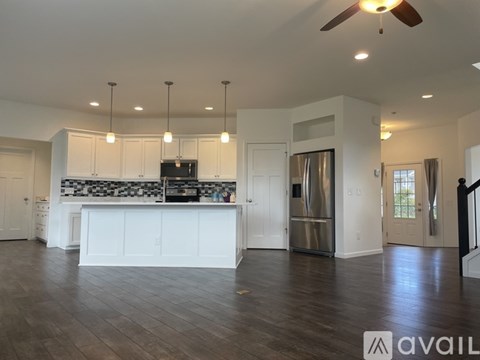 A spacious kitchen with white cabinets and a black and white backsplash.
