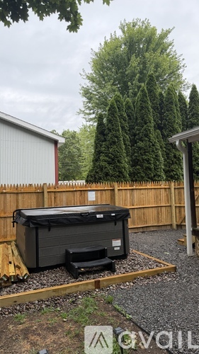 A hot tub is placed on a gravel area in a backyard.
