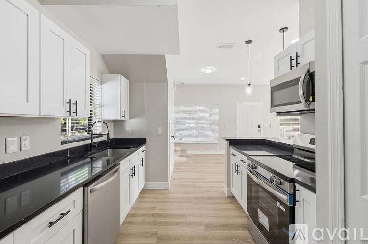 A kitchen with white cabinets and black countertops.