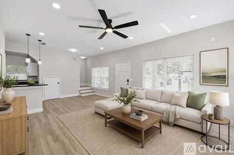 A living room with a white sofa, wooden coffee table, and a ceiling fan.