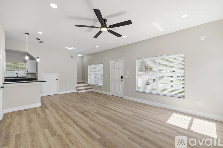 A spacious room with a ceiling fan and lighting fixtures.