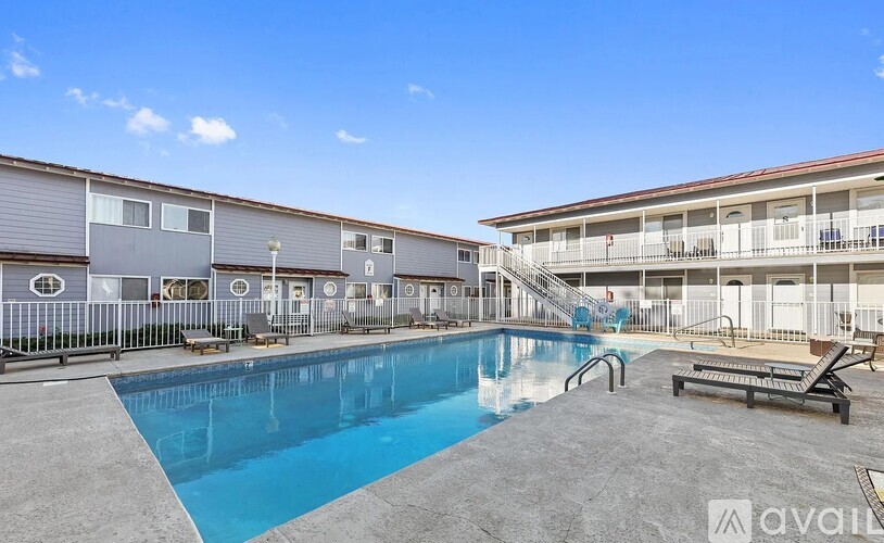 A swimming pool in front of a building with a clear blue sky.