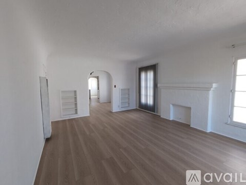 A spacious room with wooden flooring and white walls.