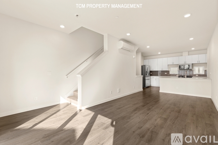 A spacious room with wooden flooring and a staircase leading to the upper level.