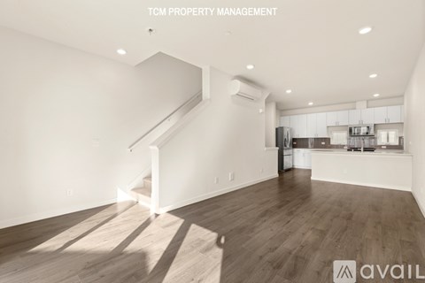 A spacious room with wooden flooring and a staircase leading to the upper level.
