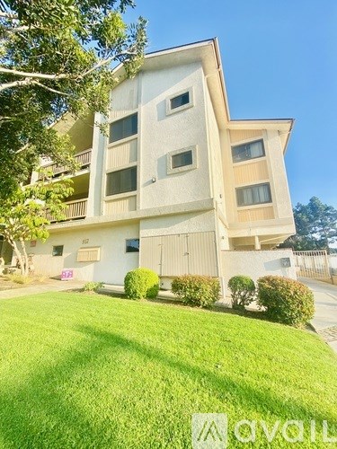 A modern apartment building with a well-maintained lawn in front.