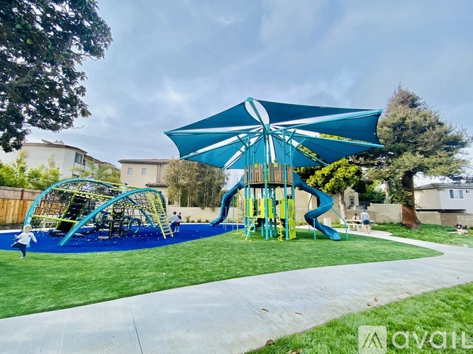 A playground with a blue umbrella and a slide.