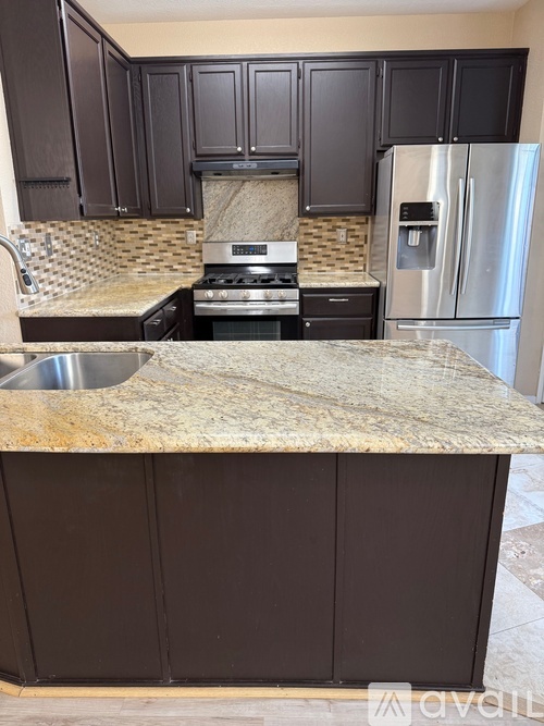 A kitchen with brown cabinets and a granite counter.