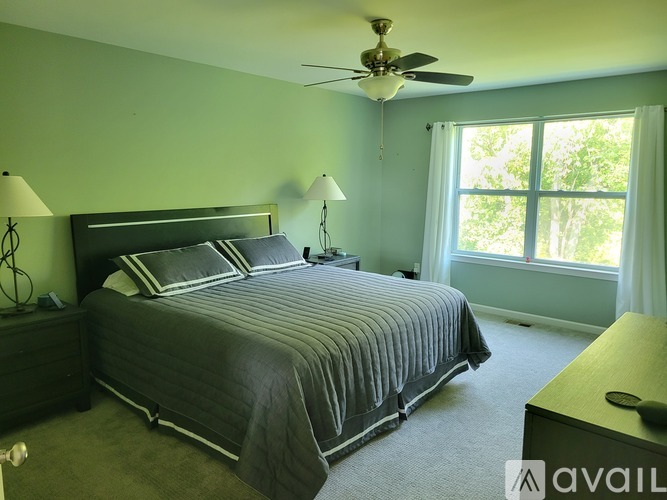 A bedroom with a large bed and a ceiling fan.