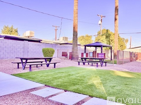 A gazebo sits in the middle of a grassy area with picnic tables on either side.