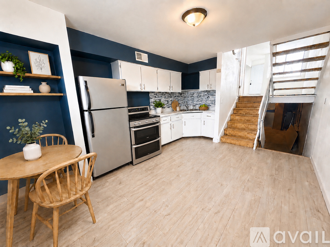 A kitchen with a refrigerator, oven, and a dining table with chairs.
