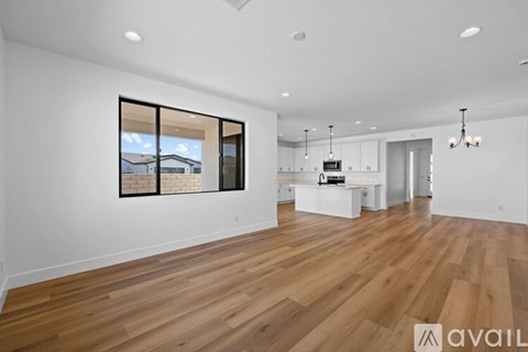 A spacious room with wooden flooring and a large window.
