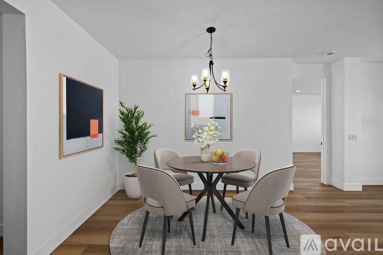 A dining room with a table set for two and a chandelier hanging from the ceiling.