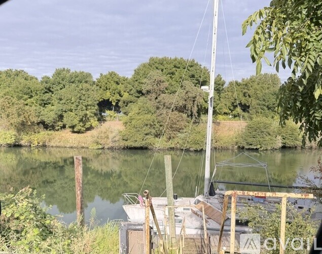 A boat is docked on a river with trees in the background.
