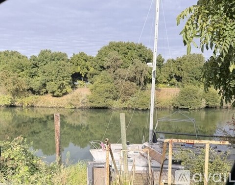 A boat is docked on a river with trees in the background.