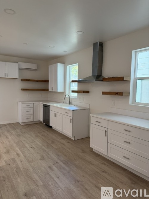 A kitchen with white cabinets and a wooden floor.