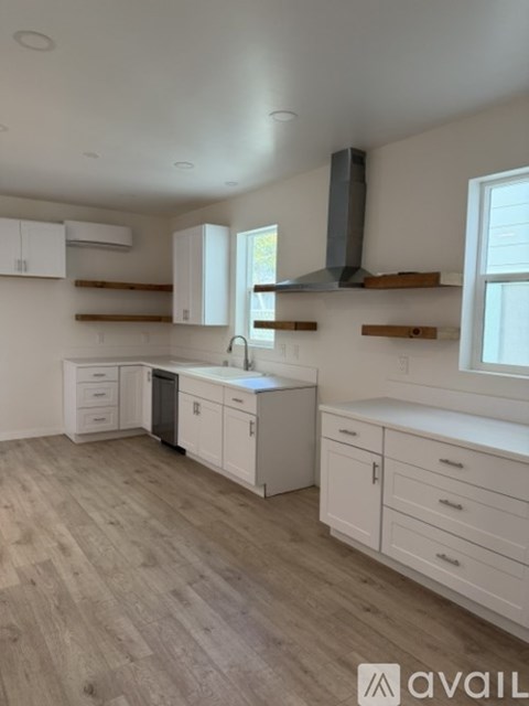 A kitchen with white cabinets and a wooden floor.