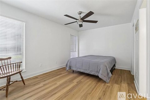A bedroom with a bed, a chair, and a ceiling fan.
