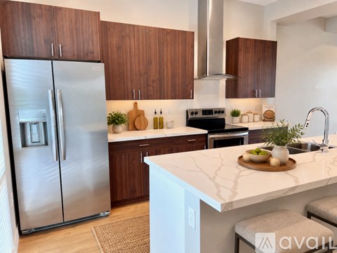 A kitchen with a stainless steel refrigerator and wooden cabinets.