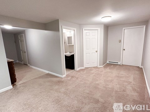 A bedroom with a white door and a carpeted floor.