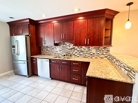 A kitchen with a granite counter top and wooden cabinets.