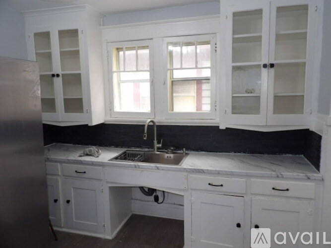 A kitchen with white cabinets and a black countertop.